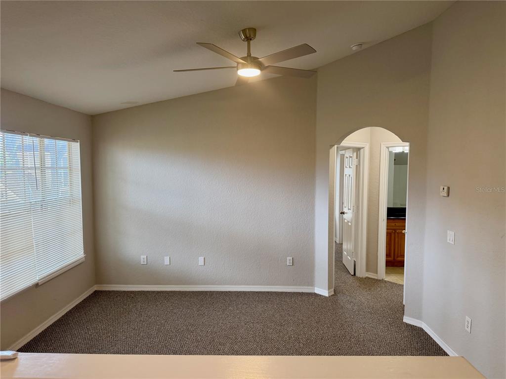 A carpeted room with a vaulted ceiling, a ceiling fan, and an arched doorway — 826 GRAND REGENCY POINT UNIT 203, ALTAMONTE SPRINGS, FL