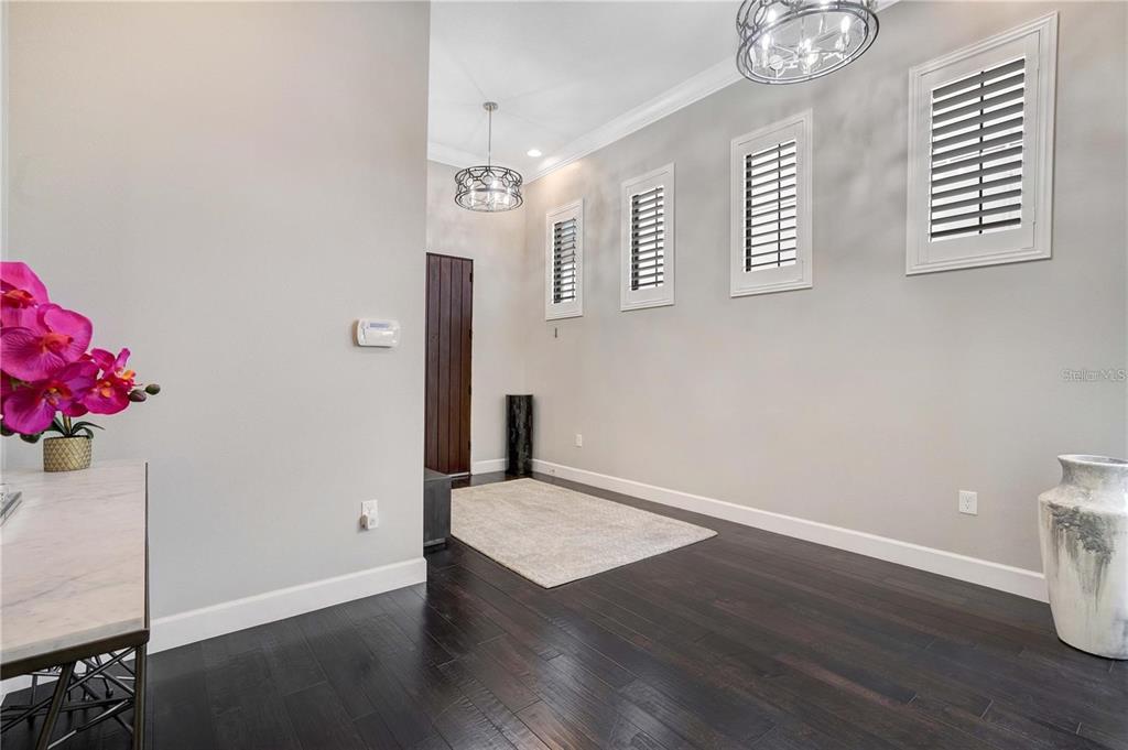 A bright entryway features dark hardwood floors, three shuttered windows, and two decorative pendant lights — 8449 VIA VITTORIA WAY, ORLANDO, FL