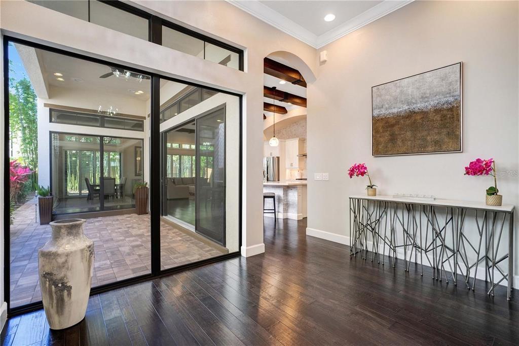 A bright foyer with dark hardwood floors leads to a kitchen through an arched doorway — 8449 VIA VITTORIA WAY, ORLANDO, FL