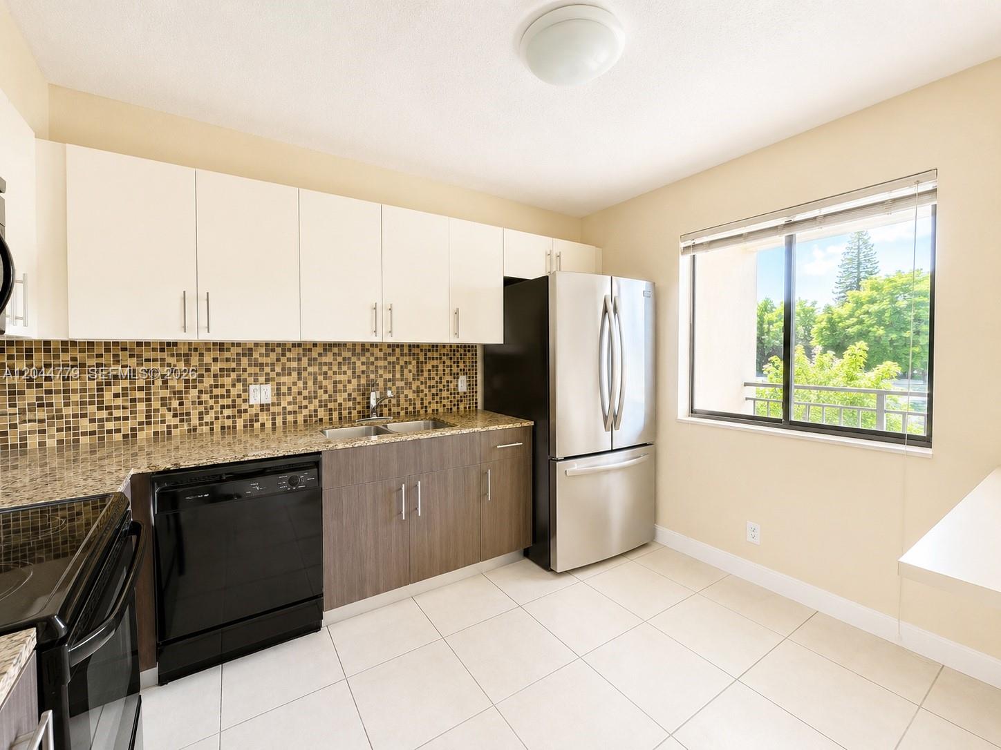 A kitchen features white upper cabinets, wood-tone lower cabinets, stainless steel appliances, and a window — 405 LAKEVIEW DR # 202, Weston FL 33326, WESTON, FL