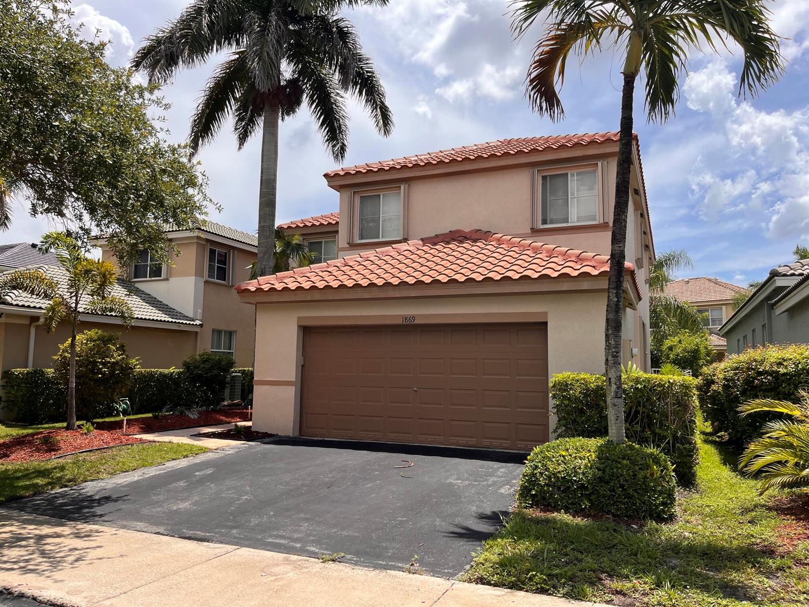 A two-story house with a brown garage door, tan stucco walls, and a tiled roof — 1869 Aspen Lane, Weston FL 33327, WESTON, FL