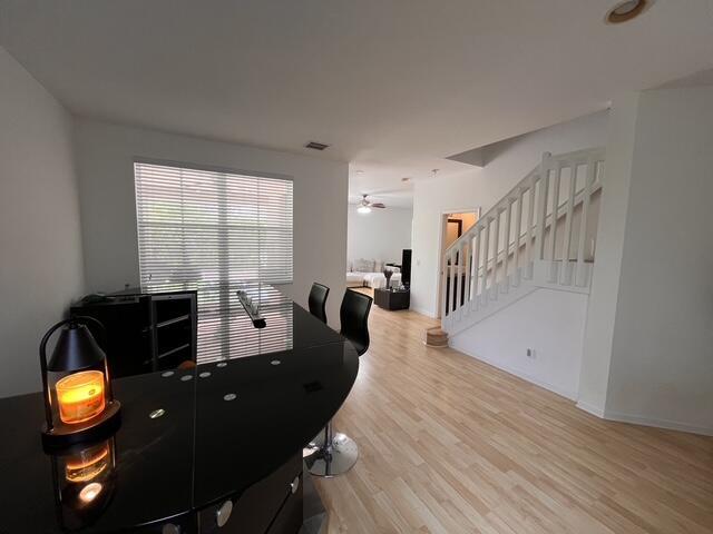 A modern kitchen features a black curved island, light wood flooring, and a staircase — 1869 Aspen Lane, Weston FL 33327, WESTON, FL