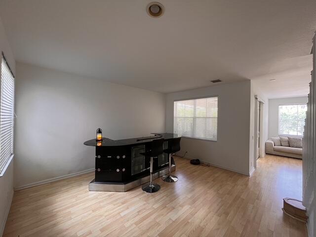 A room with light wood flooring features a black bar counter and two bar stools — 1869 Aspen Lane, Weston FL 33327, WESTON, FL
