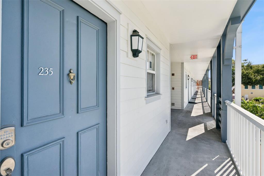 A blue door labeled 235 opens onto an outdoor concrete walkway with white railings — 720 CELEBRATION AVENUE UNIT 235, CELEBRATION, FL