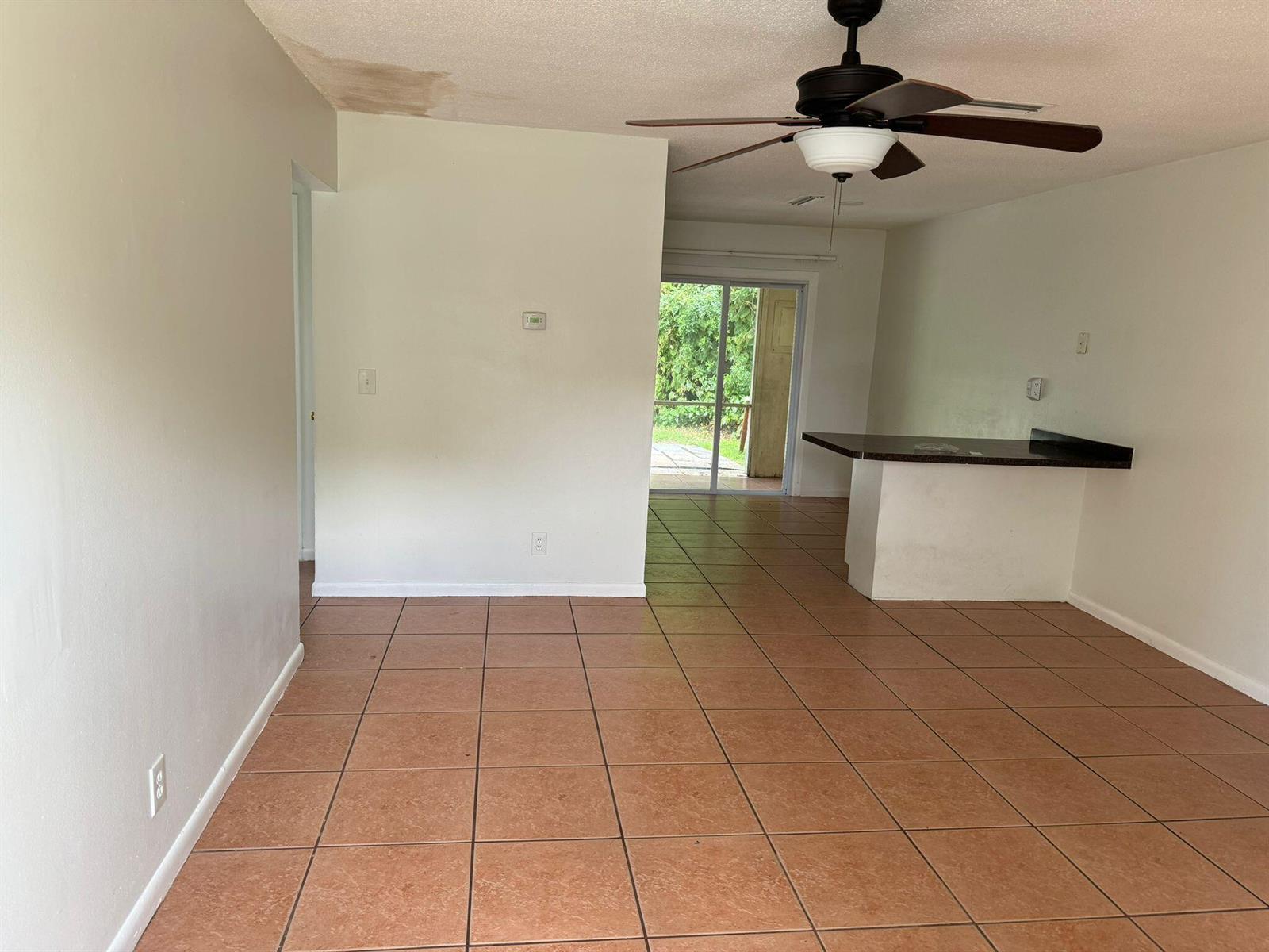 An open living area features tile flooring, a ceiling fan, and a kitchen breakfast bar — 3002 SE Camino Avenue, Stuart FL 34997, STUART, FL