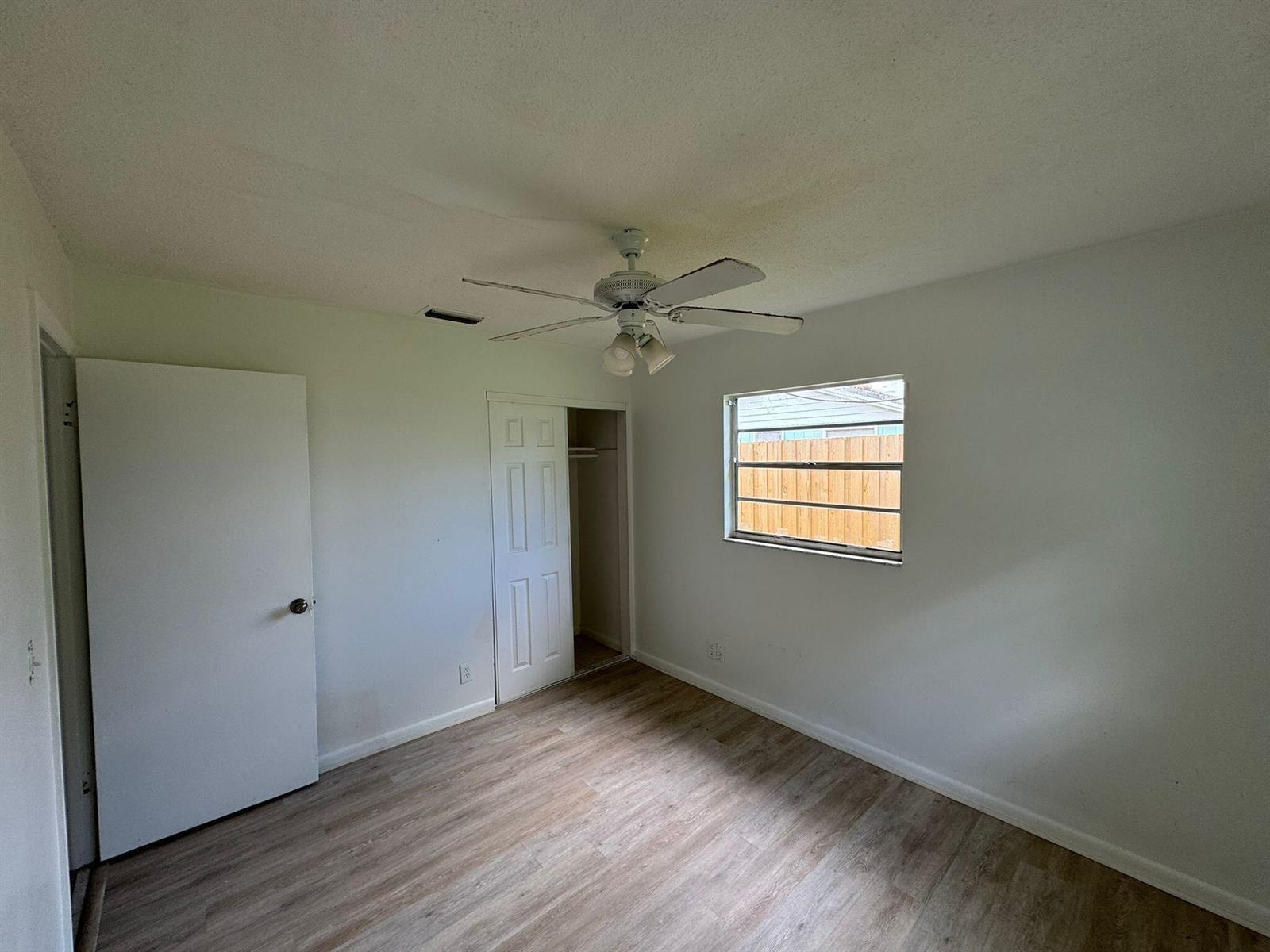 A bedroom with white walls, wood-look flooring, a ceiling fan, and a closet — 3002 SE Camino Avenue, Stuart FL 34997, STUART, FL