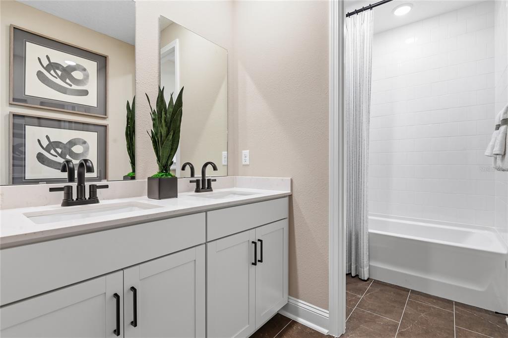 A bathroom features a double vanity with white cabinets, quartz countertops, and a shower-tub combo — 203 THORNBERRY WAY, PALM COAST, FL