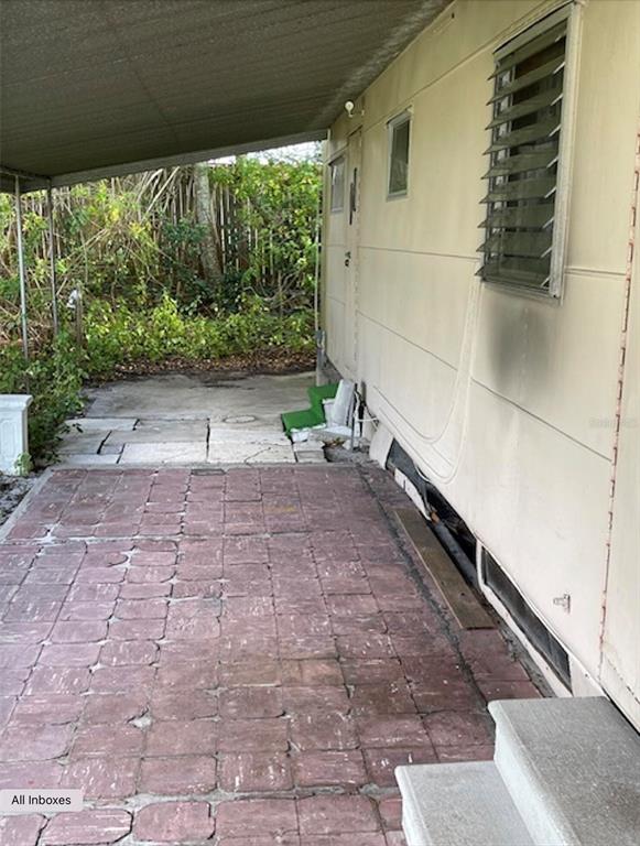 A mobile home exterior features a covered patio with brick pavers and a metal awning — 9736 WARRICK STREET, PORT RICHEY, FL