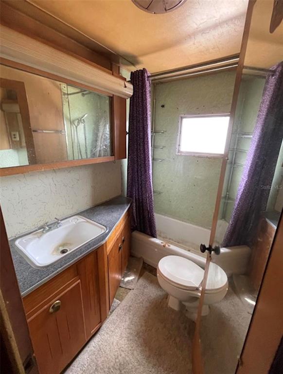 A dated bathroom features a wood vanity, a sink, a toilet, and a shower-tub combination — 9736 WARRICK STREET, PORT RICHEY, FL
