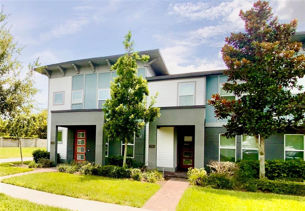 A two-story duplex with gray and white siding, flat roofs, and two front entry doors — 7206 CARRICKBEND LANE, ORLANDO, FL