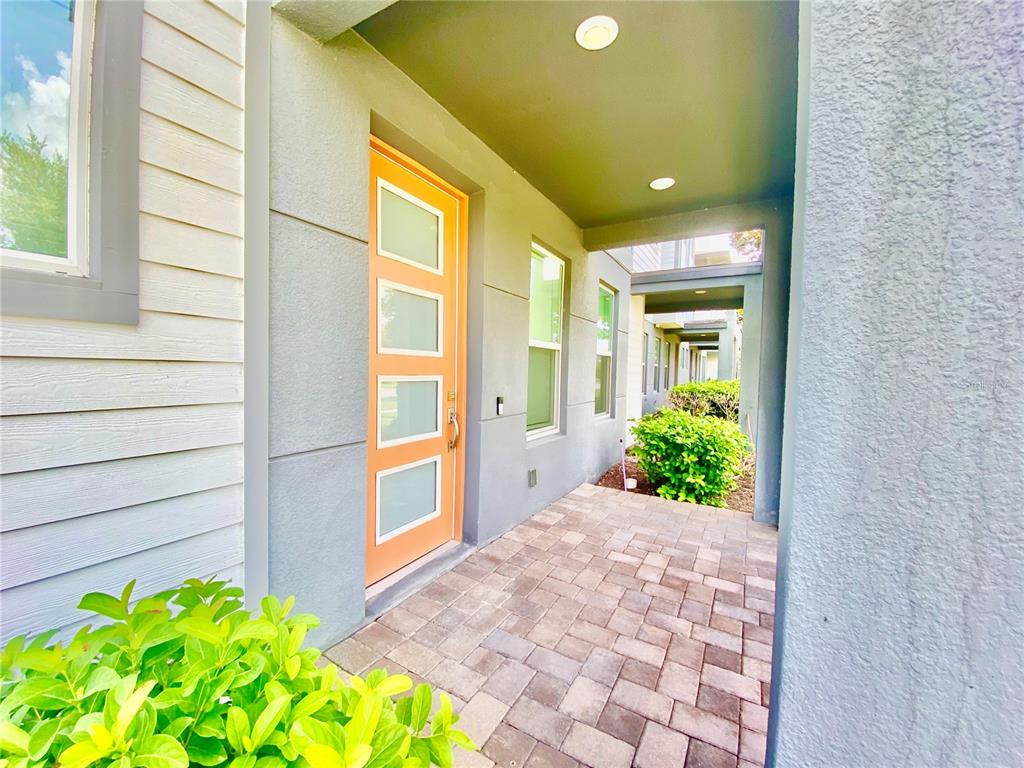 A paved entryway features a modern orange front door with four glass panels — 7206 CARRICKBEND LANE, ORLANDO, FL