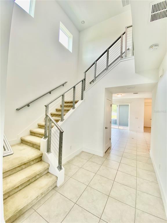 An interior view shows a carpeted staircase with a metal railing leading to an upper level — 7206 CARRICKBEND LANE, ORLANDO, FL