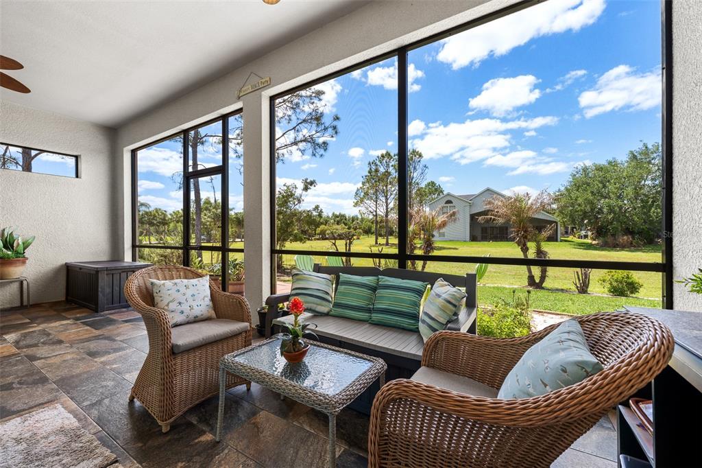 A screened-in patio with wicker furniture, tile flooring, and a view of a grassy yard — 4501 ROLLING GREEN DRIVE, WESLEY CHAPEL, FL