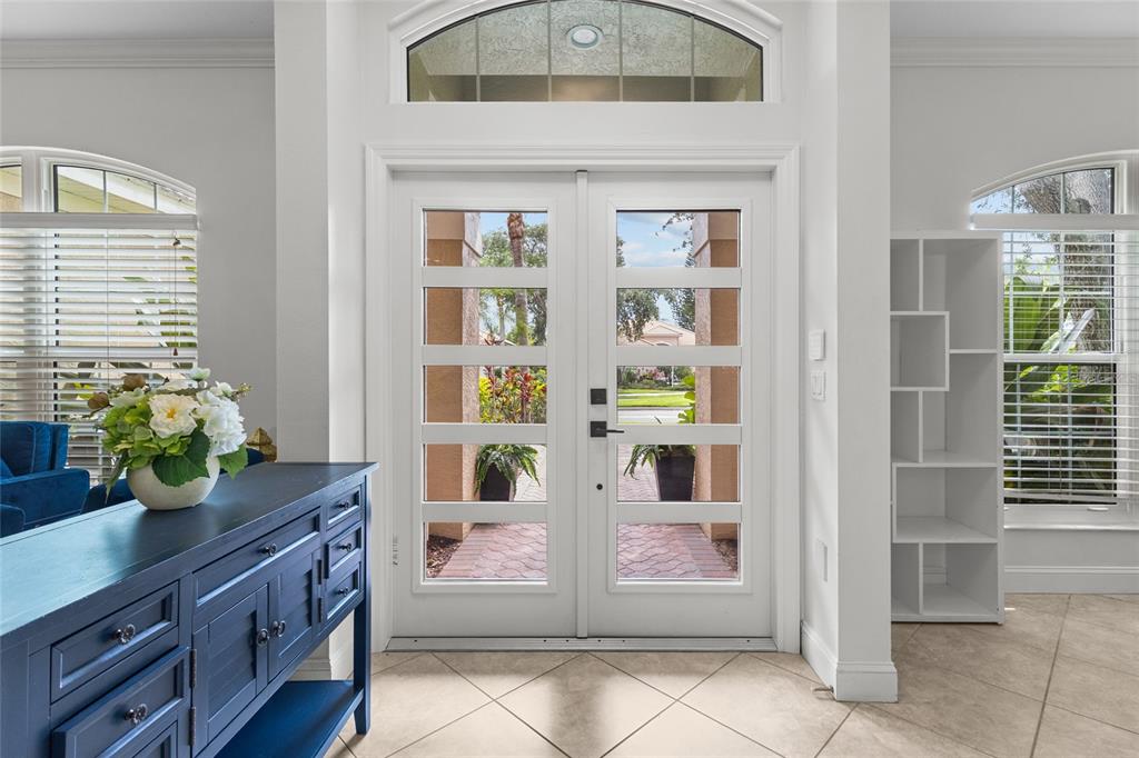 A bright entryway features double glass-paneled doors, a blue console table, and tile flooring — 7627 DESERT INN WAY, BRADENTON, FL