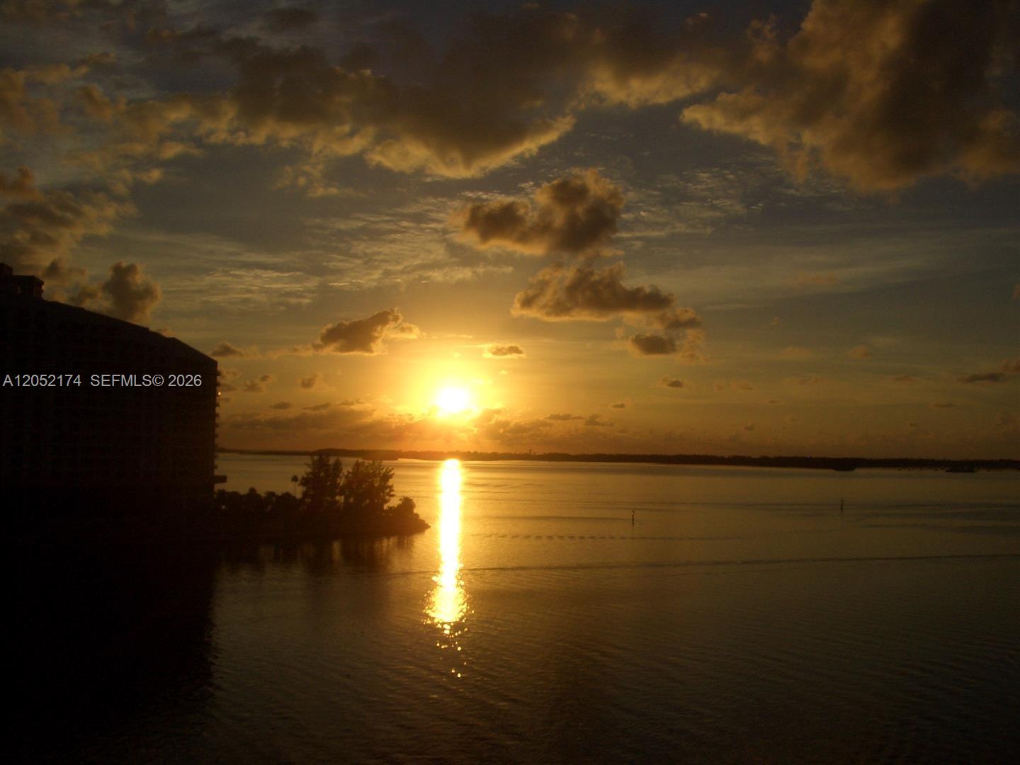 A sunset view over a body of water with a building silhouette on the left — 999 Brickell Bay Dr # 1904, Miami FL 33131, MIAMI, FL