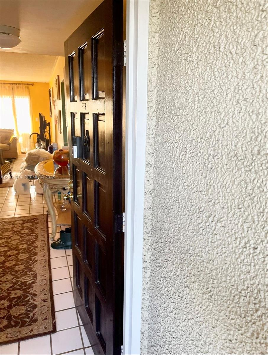 A dark wooden door opens into a tiled living area with a patterned rug — 3301 Spanish Moss Ter # 510, Lauderhill FL 33319, LAUDERHILL, FL