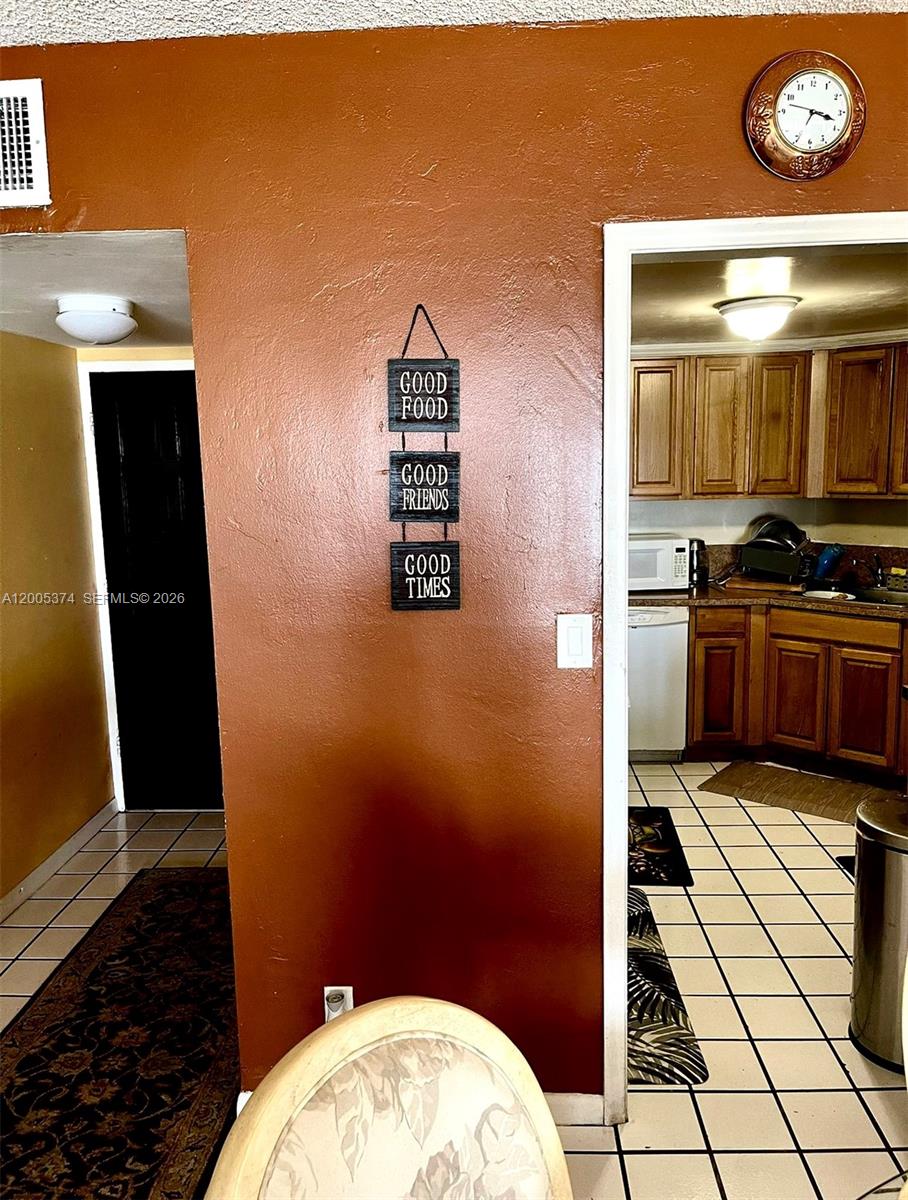 A wall with a hanging sign separates a kitchen with wooden cabinets from a hallway — 3301 Spanish Moss Ter # 510, Lauderhill FL 33319, LAUDERHILL, FL