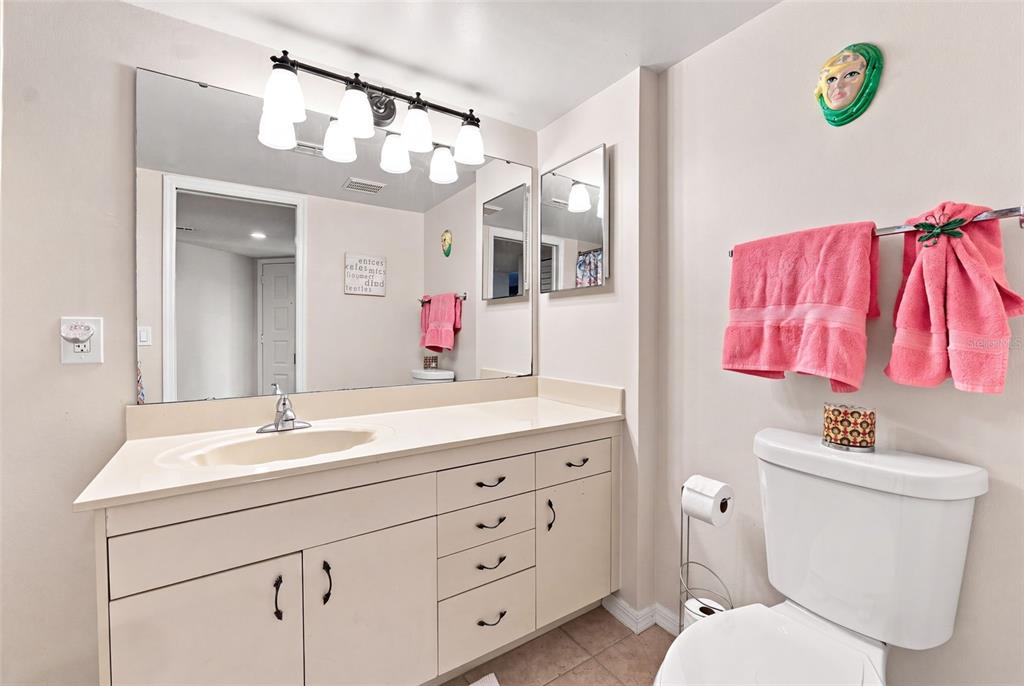 A bathroom features a vanity with a beige countertop, a large mirror, and pink towels — 3601 S BANANA RIVER BOULEVARD UNIT A304, COCOA BEACH, FL