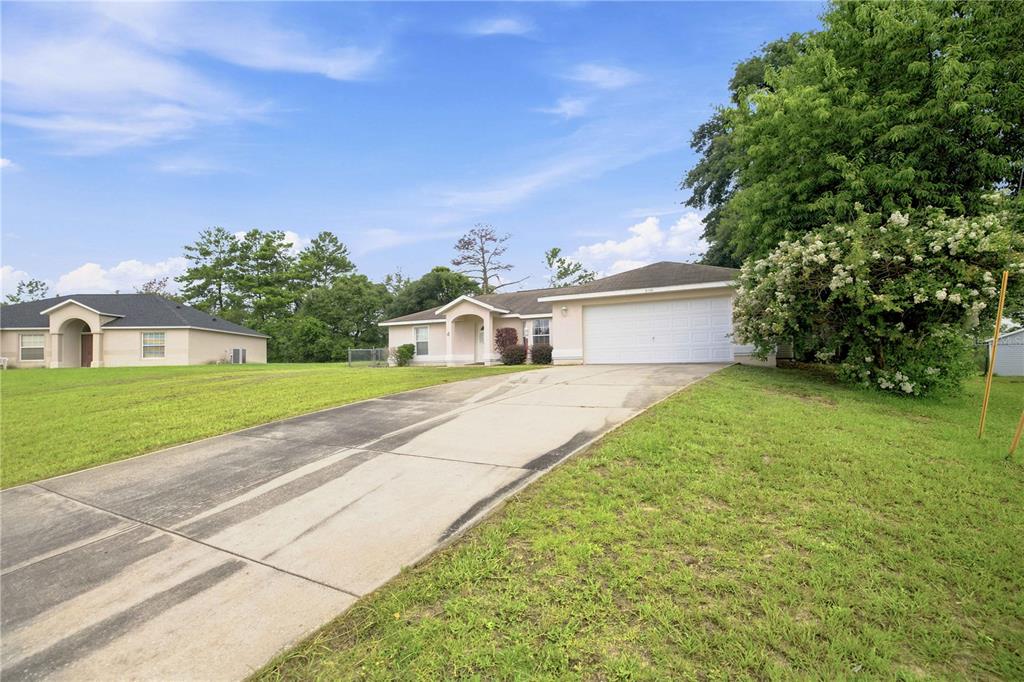 A single-story house with a white garage and a concrete driveway sits on a lawn — 3377 SW 126TH LANE ROAD, OCALA, FL