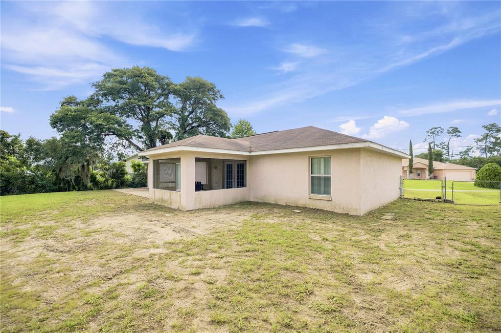The exterior of a beige stucco house features a screened-in porch and a grassy yard — 3377 SW 126TH LANE ROAD, OCALA, FL