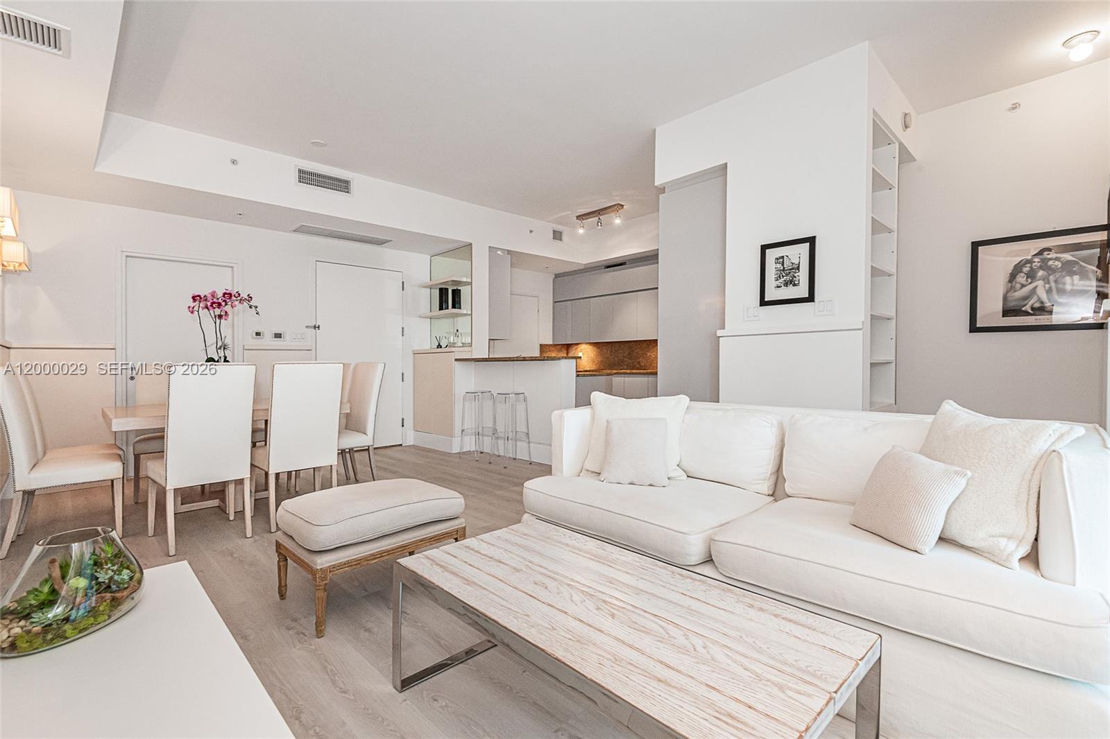 A bright living and dining area features white furniture, light wood flooring, and a kitchen — 50 S Pointe Dr # 1804, Miami Beach FL 33139, MIAMI BEACH, FL