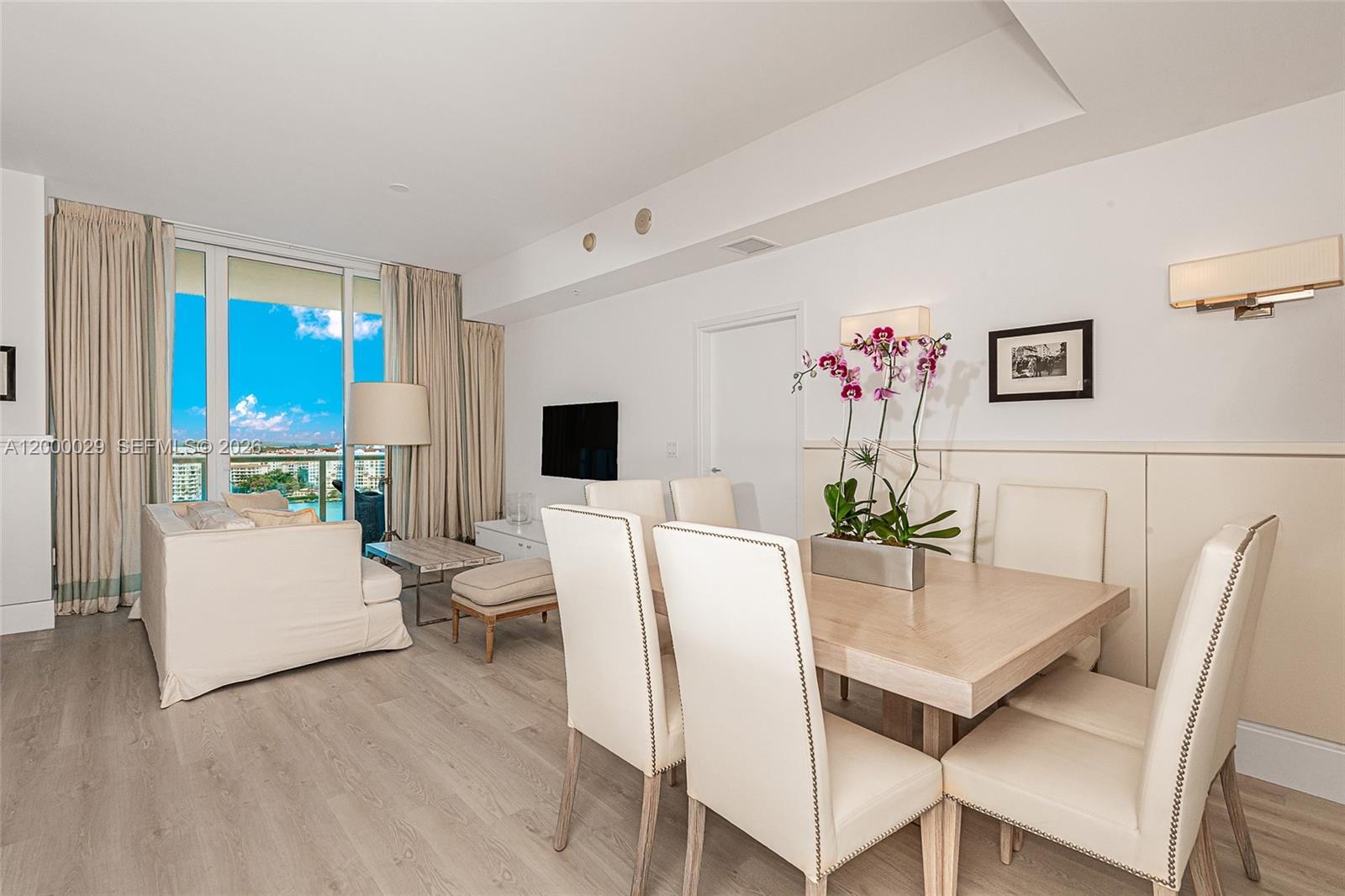 A dining area and living space feature light wood floors, neutral furniture, and a balcony view — 50 S Pointe Dr # 1804, Miami Beach FL 33139, MIAMI BEACH, FL