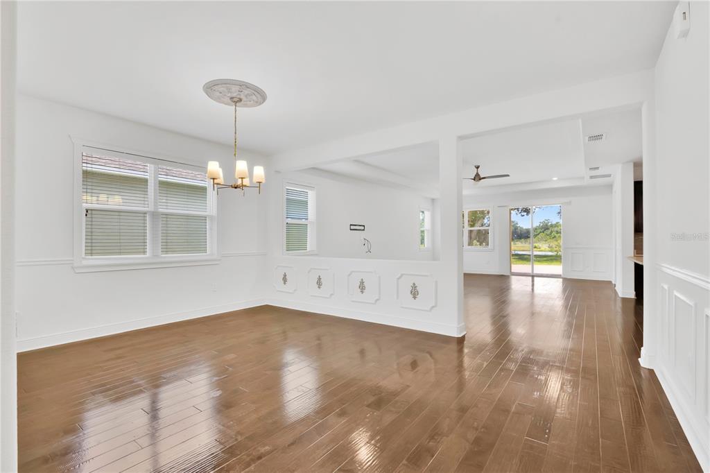 A dining room with hardwood floors, a chandelier, and a half-wall opening to a living area — 14254 SERANOA DRIVE, ORLANDO, FL