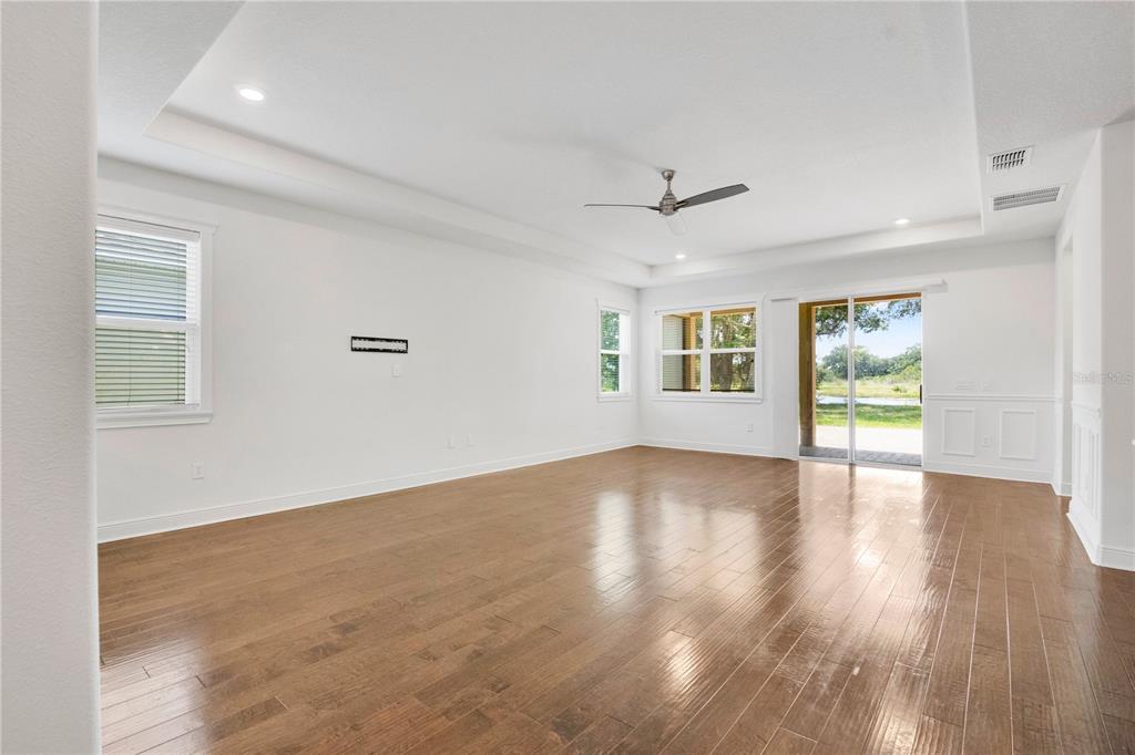 A spacious living room features white walls, hardwood floors, a tray ceiling, and sliding glass doors — 14254 SERANOA DRIVE, ORLANDO, FL