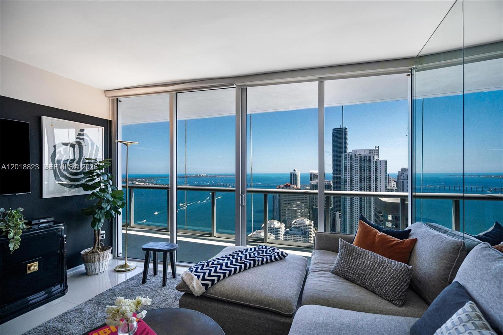 A living room features a grey sectional sofa, a black accent wall, and floor-to-ceiling windows — 495 Brickell Ave # 4911, Miami FL 33131, MIAMI, FL