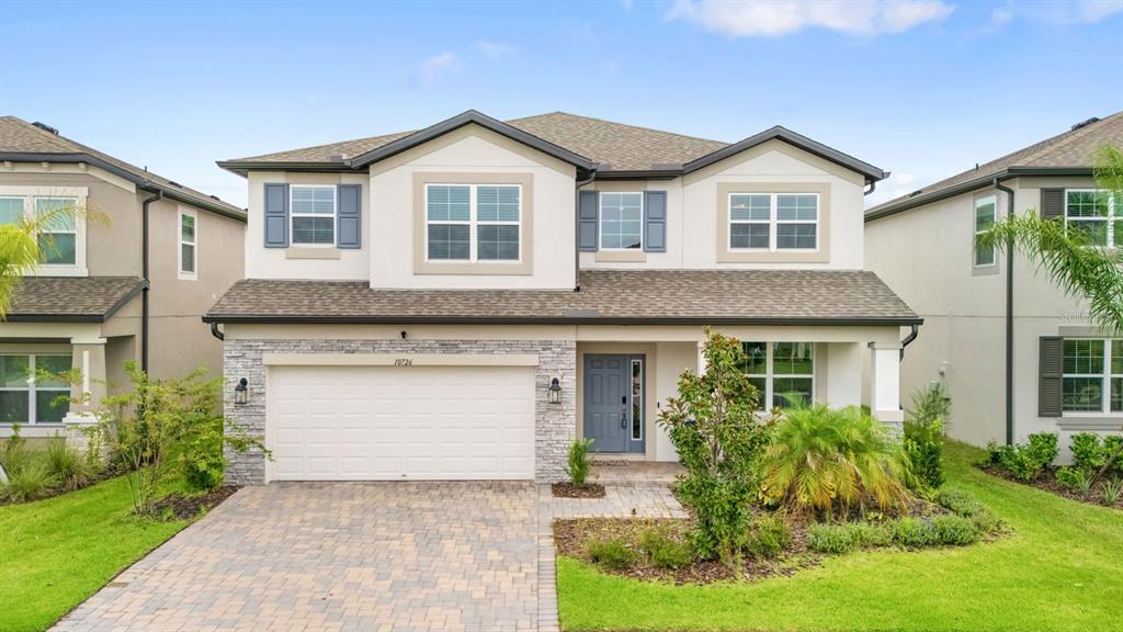 A two-story suburban house with a stone-accented facade, a two-car garage, and a paved driveway — 10726 NEW MORNING DRIVE, TAMPA, FL
