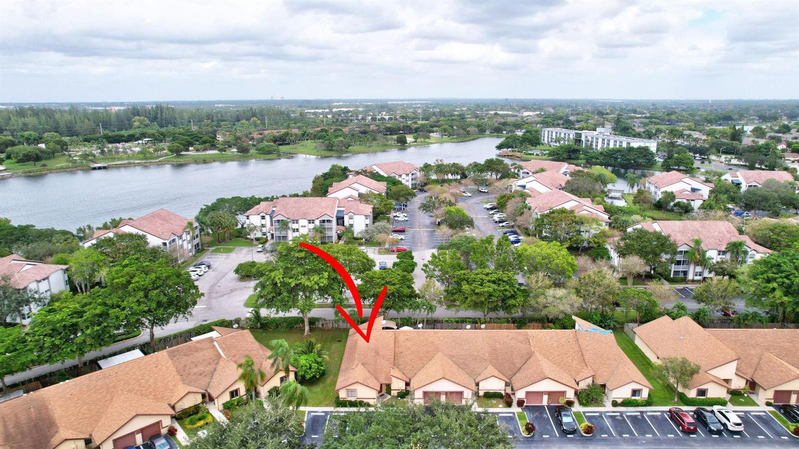 An aerial view shows a residential complex with brown-roofed townhomes, parking lots, and a lake — 11145 NW 38th Place, Sunrise FL 33351, SUNRISE, FL
