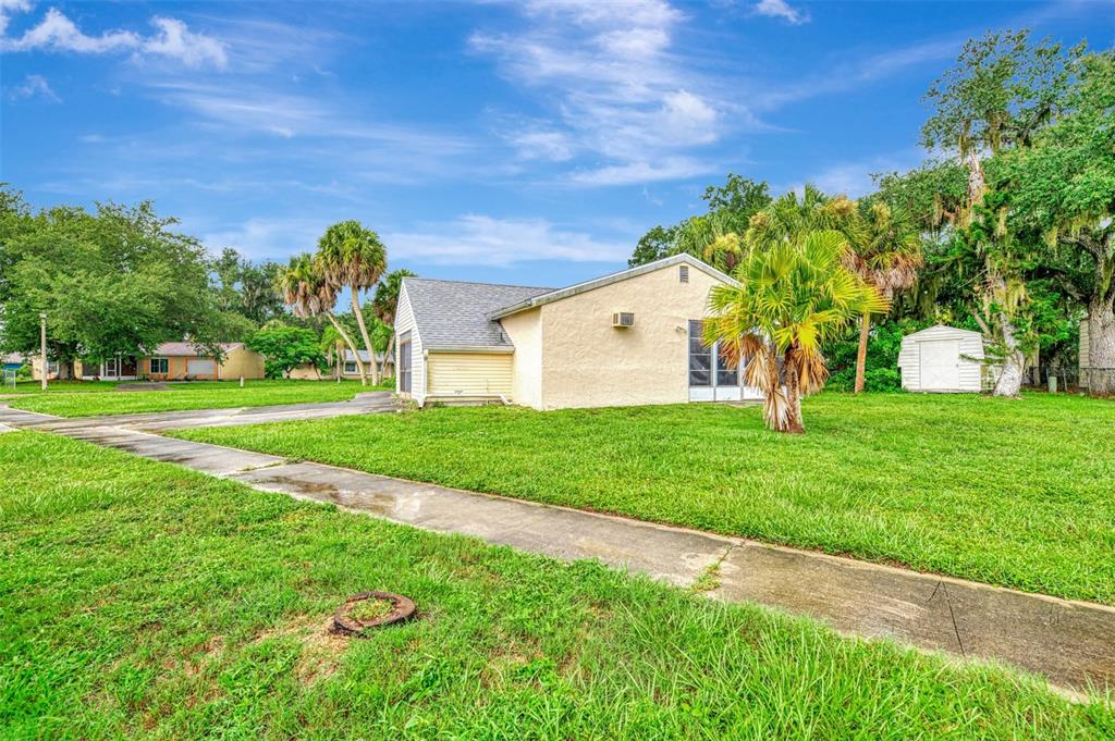 A light-colored house with a screened porch sits on a grassy lot with palm trees — 5285 BROPHY STREET, NORTH PORT, FL