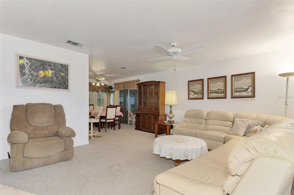 A living room features a beige sectional sofa, a recliner, and an adjacent dining area — 5285 BROPHY STREET, NORTH PORT, FL