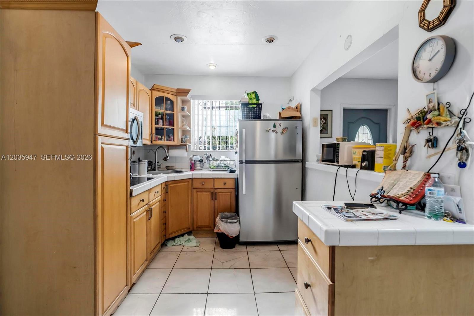 A kitchen features light wood cabinets, white tile countertops, and stainless steel appliances — 2300 NW 9th St, Miami FL 33125, MIAMI, FL