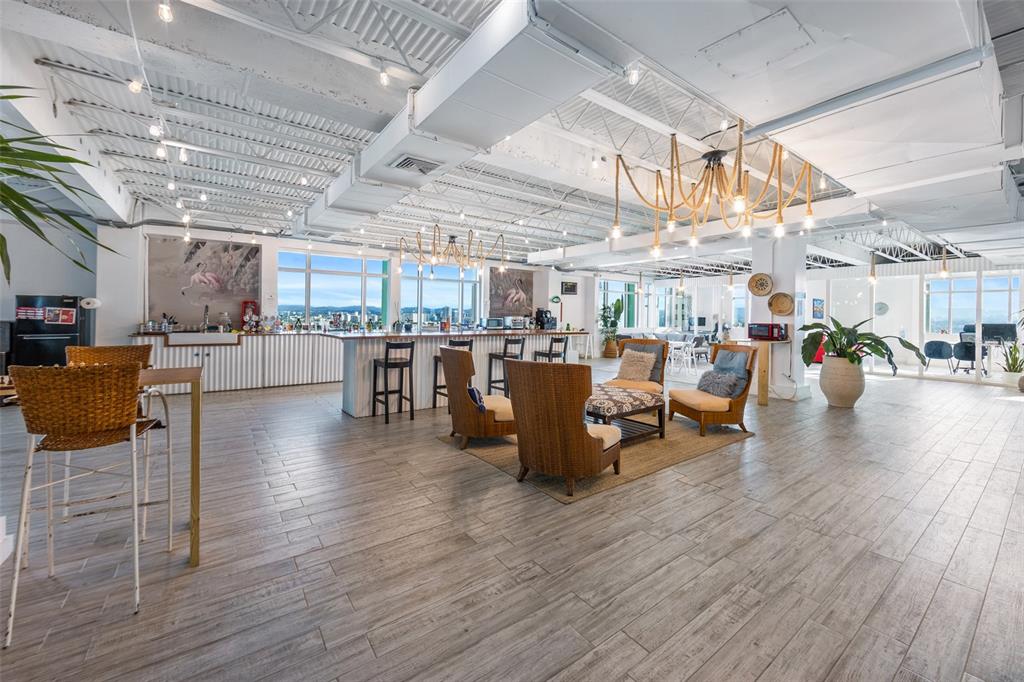 An open-plan office space features a kitchen area, lounge seating, and large windows with views — 1519, Parada 23 AVE. PONCE DE LEÓN, ESQ CALLE DEL PARQUE, SAN JUAN, PR