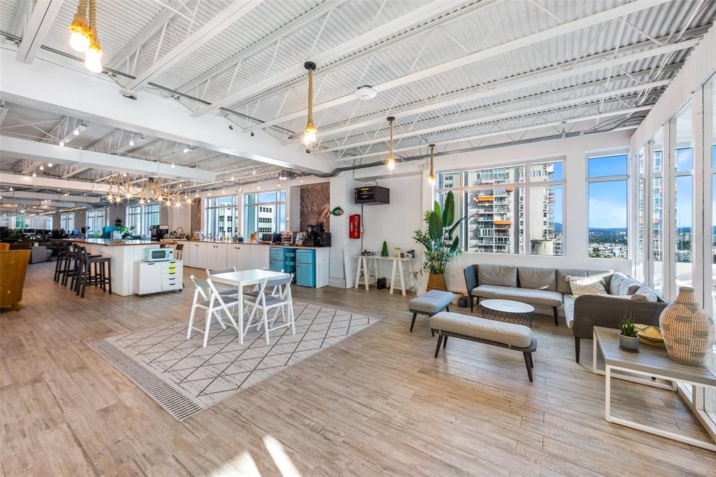 A bright, open-concept office break room features wood-look flooring, exposed ceiling trusses, and city views — 1519, Parada 23 AVE. PONCE DE LEÓN, ESQ CALLE DEL PARQUE, SAN JUAN, PR