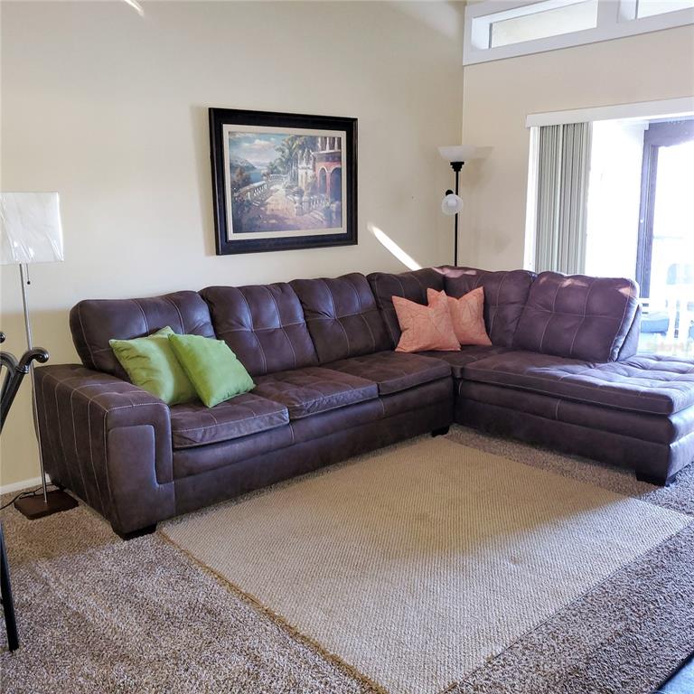 A living room features a large brown sectional sofa, a beige area rug, and artwork — 272 WOODLAKE WYNDE UNIT 272, OLDSMAR, FL
