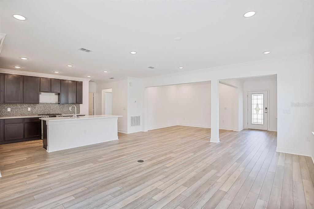 An open-concept kitchen with dark cabinets and a white island overlooks a spacious living area — 833 SW 80TH WAY, GAINESVILLE, FL