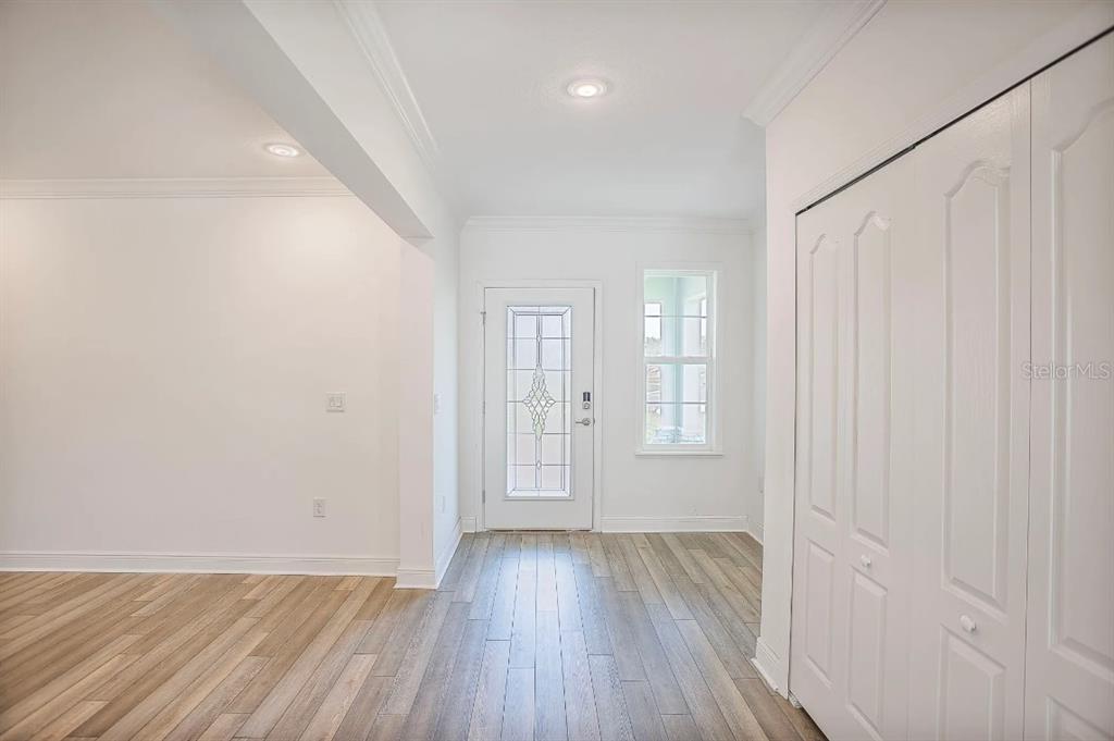 An entryway features light wood-look flooring, a white front door with glass, and a closet — 833 SW 80TH WAY, GAINESVILLE, FL