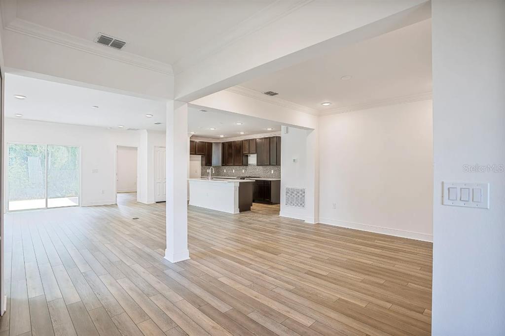 An open-concept living area features light wood-look flooring and a view into the kitchen — 833 SW 80TH WAY, GAINESVILLE, FL