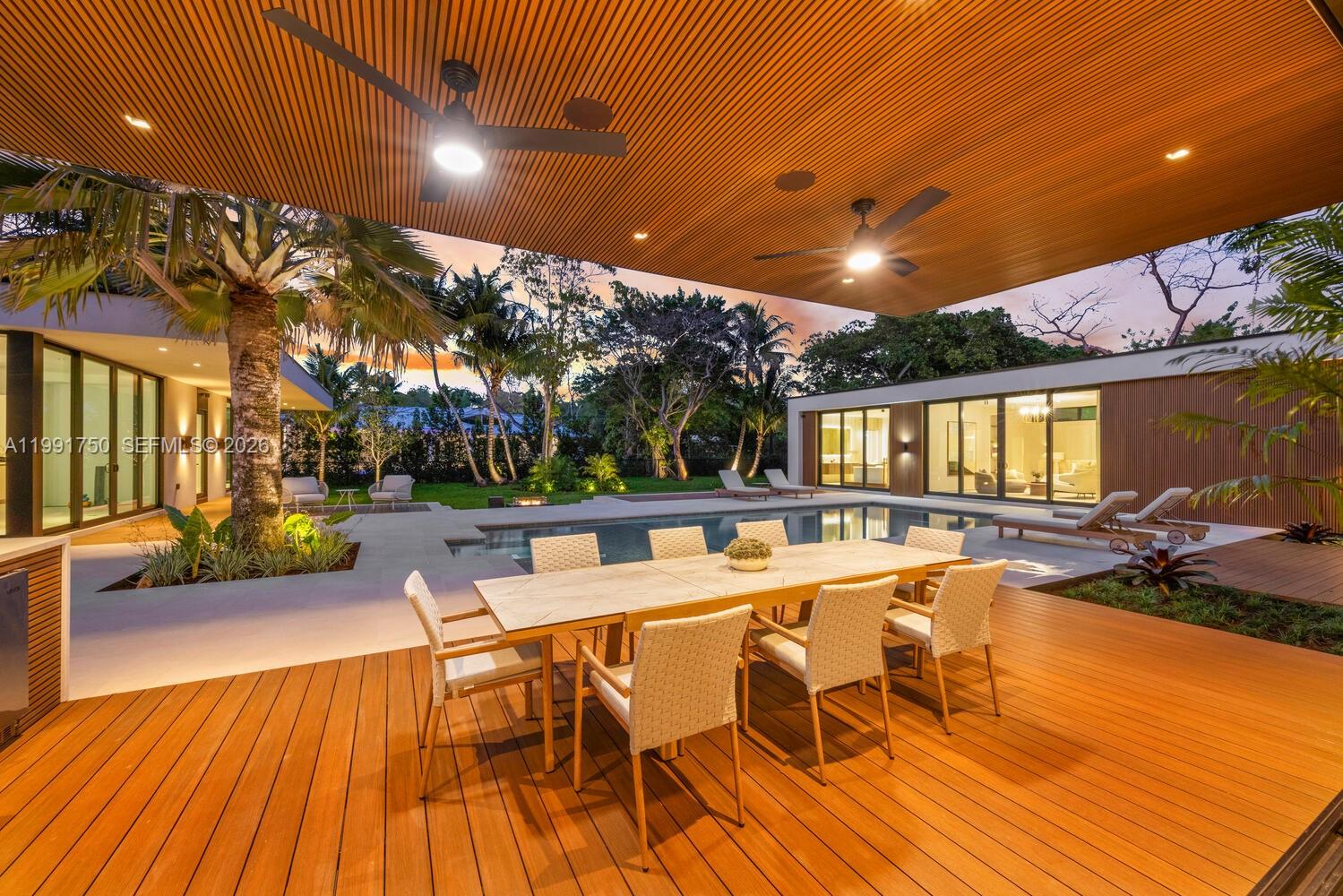 A modern outdoor patio features a dining set, swimming pool, and wood-paneled ceiling — 7901 SW 120th St, Pinecrest FL 33156, PINECREST, FL