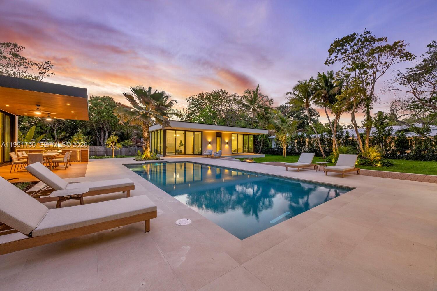 A modern house features a rectangular swimming pool, lounge chairs, and a covered outdoor dining area — 7901 SW 120th St, Pinecrest FL 33156, PINECREST, FL