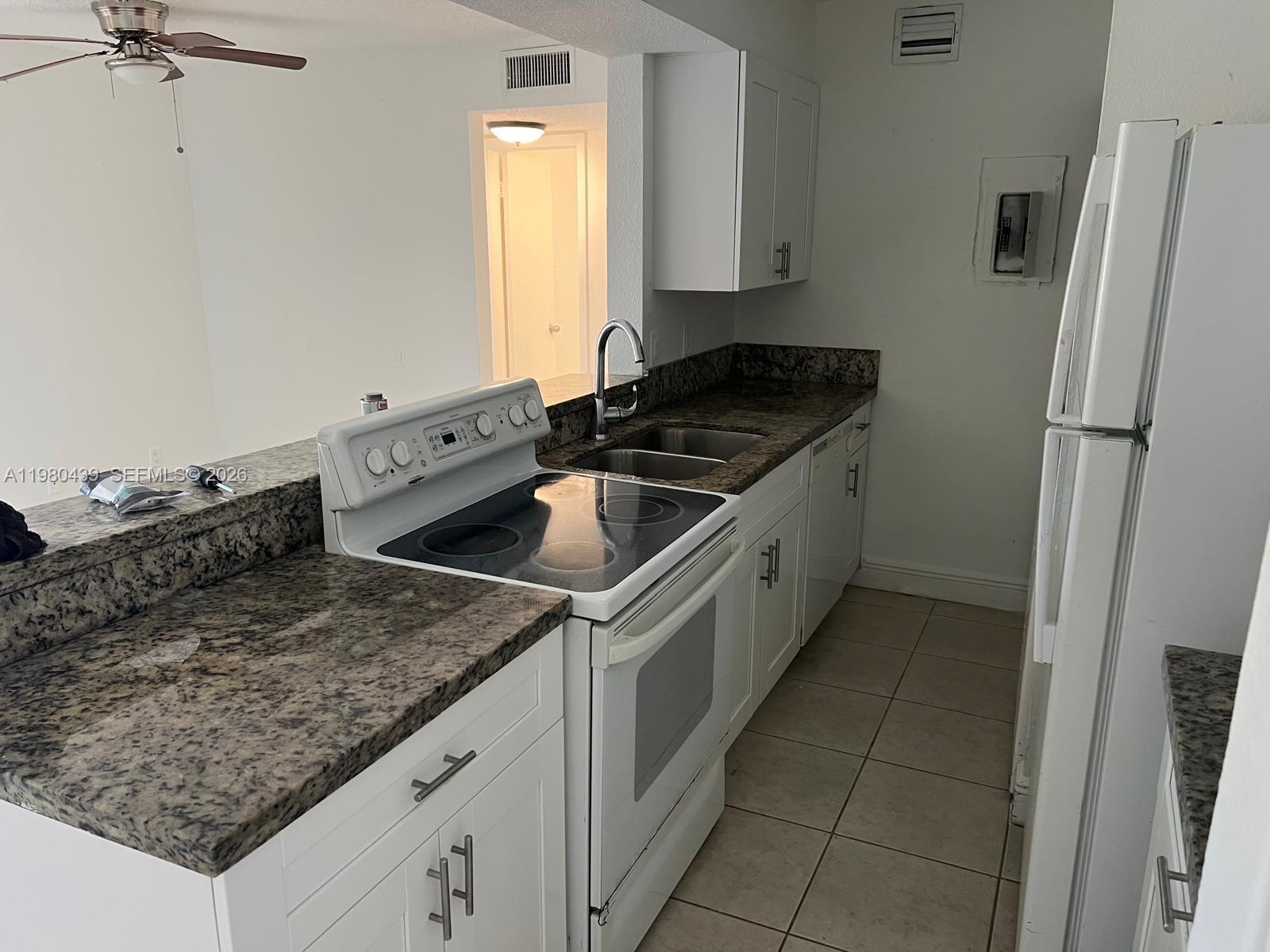 A kitchen features white cabinets, granite countertops, a white stove, and a white refrigerator — 4435 Treehouse Ln # H, Tamarac FL 33319, TAMARAC, FL