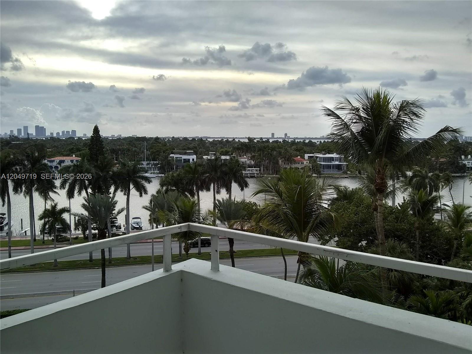 A balcony overlooks a road, a waterway, palm trees, and a distant city skyline — 5161 Collins Ave # 809, Miami Beach FL 33140, MIAMI BEACH, FL
