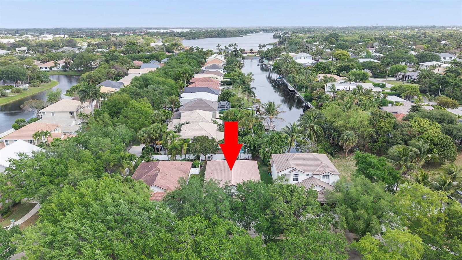 An aerial view shows a residential house with a tan roof marked by a red arrow — 981 Delray Lakes Drive, Delray Beach FL 33444, DELRAY BEACH, FL
