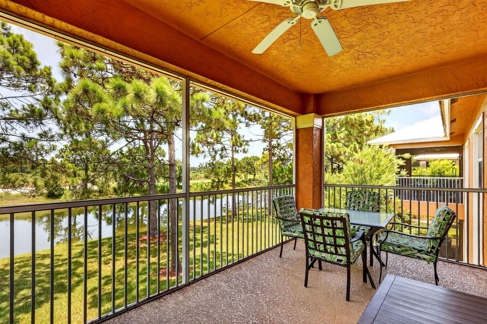 A screened-in balcony features a dining set, ceiling fan, and views of a pond — 8326 Mulligan Circle # 2123, FL 34986, FL