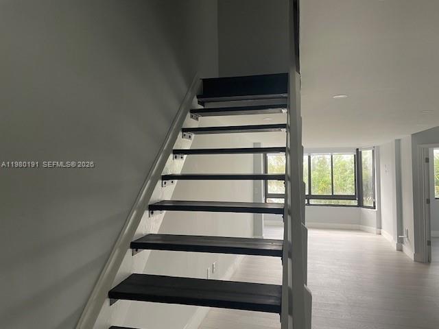 A modern staircase with dark wooden treads and white railings leads to an upper level — 8305 SW 152nd Ave # 406, Miami FL 33193, MIAMI, FL