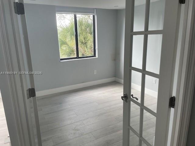 A room with light-colored wood-look flooring and a window viewed through French doors — 8305 SW 152nd Ave # 406, Miami FL 33193, MIAMI, FL