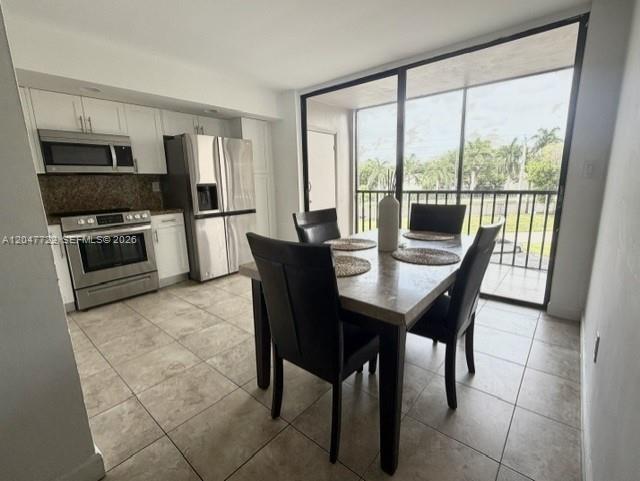 A dining area with a table and chairs sits adjacent to a modern stainless steel kitchen — 8700 SW 133rd Ave Rd # 302, Miami FL 33183, MIAMI, FL