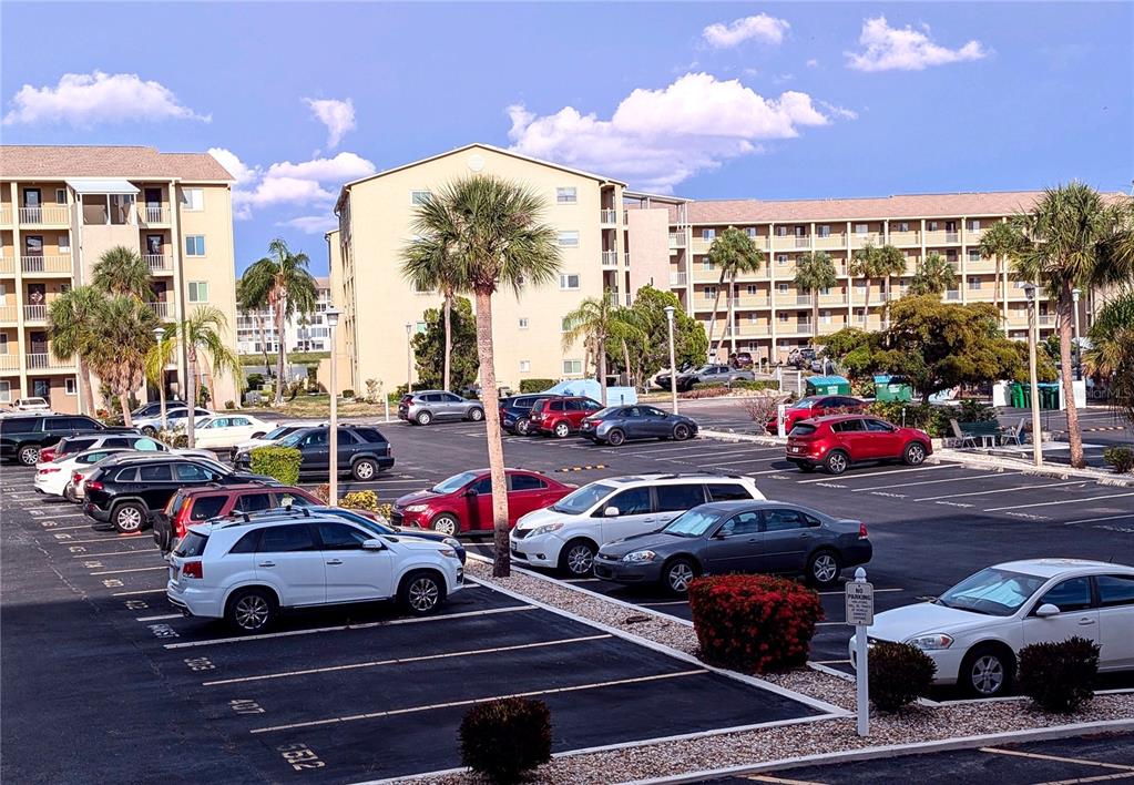 A multi-story apartment complex overlooks a paved parking lot filled with various parked cars — 3564 LAKE BAYSHORE DRIVE UNIT K-203, BRADENTON, FL